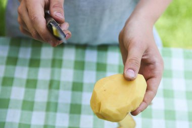 Çocuk detayını soyma taze sarı patates mutfak bıçağıyla eller.. 