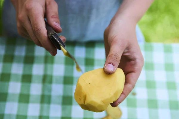 Detalle de las manos de los niños pelando papas amarillas frescas con cuchillo de cocina . — Foto de Stock