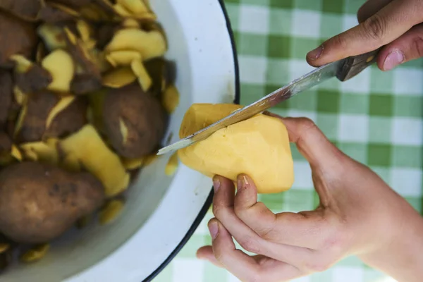 Çocuk detayını soyma taze sarı patates mutfak bıçağıyla eller. Dışarıda bahçede. 