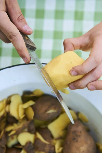 Çocuk detayını soyma taze sarı patates mutfak bıçağıyla eller. Dışarıda bahçede. 