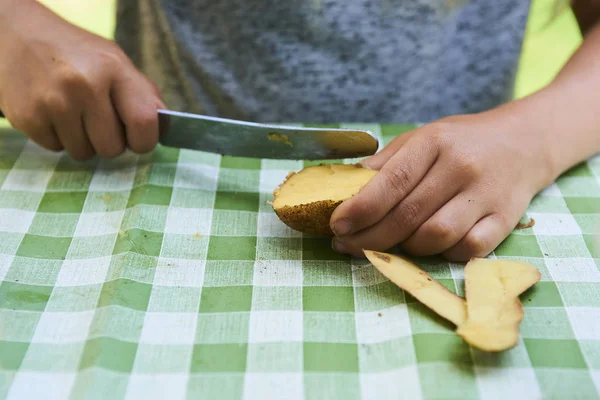 Çocuk detayını soyma taze sarı patates mutfak bıçağıyla eller. Dışarıda bahçede. 