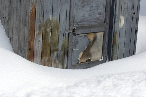 old village wooden hut with door and lock, snow covered land