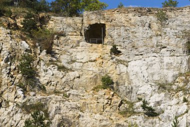 Kayalık uçurumlardaki mağara oluşumu yaz mevsiminde manzara, yeşil ağaçlar 