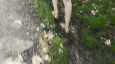 Arka plan, çıplak ayaklı bir çocuğun orman çamurunda yürüdüğü görüntüler.