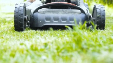 Çayırda çim biçme makinesi, arka planda erkek bacakları. 