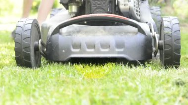 Çayırda çim biçme makinesi, arka planda erkek bacakları. 