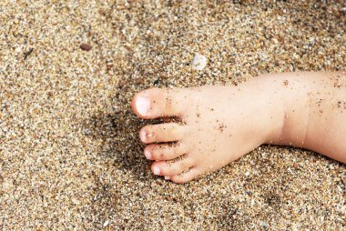 Kumsalın yüzeyindeki bebek ayak parmakları