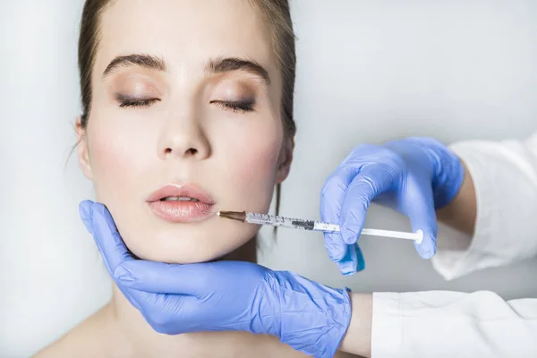 Doctor aesthetician makes lips correction and augmentation to female patient — Stock Photo, Image