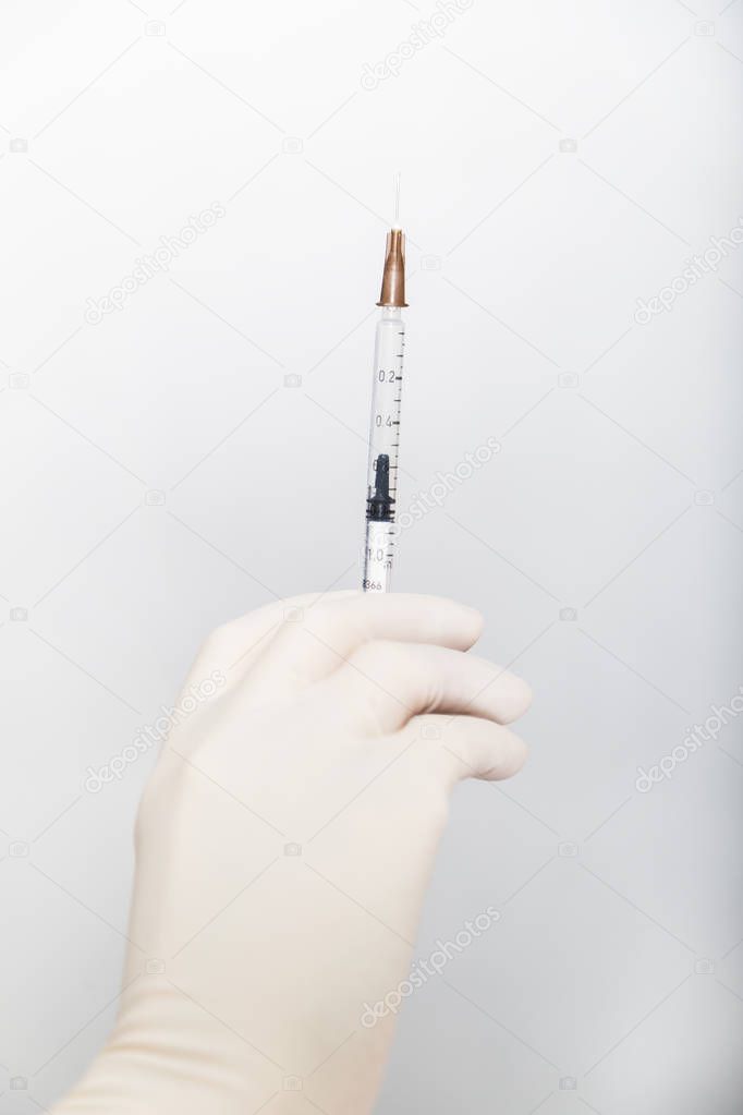 Hand of doctor in white glove holds syringe with needle