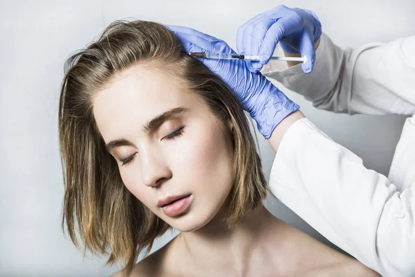 Médico esteticista hace inyecciones de belleza de la cabeza a hermosa paciente femenina — Foto de Stock