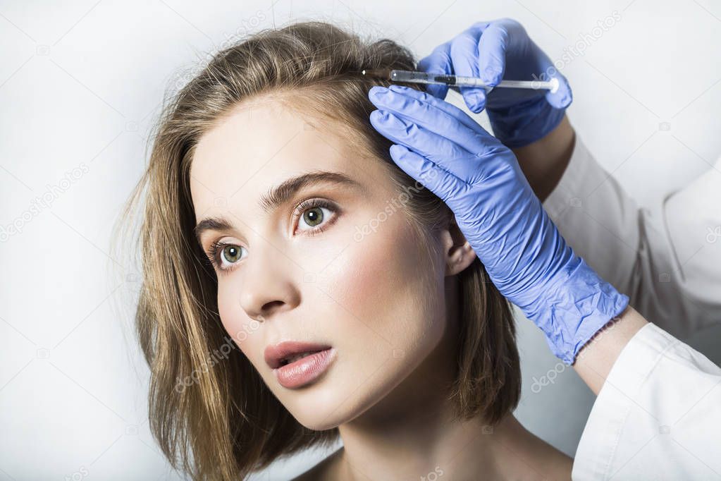 Doctor aesthetician makes head beauty injections to beautiful female patient