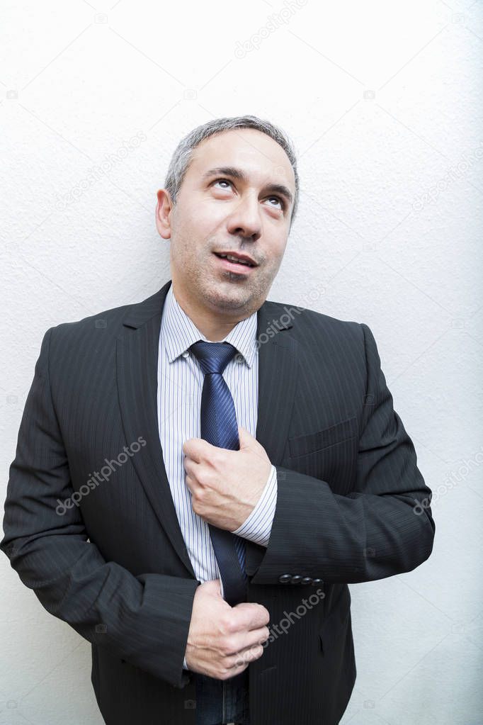 Funny man look up in suit holding tie with hands