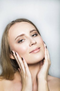 Yüzünde elleri olan güzel sarışın bir kızın portresi.