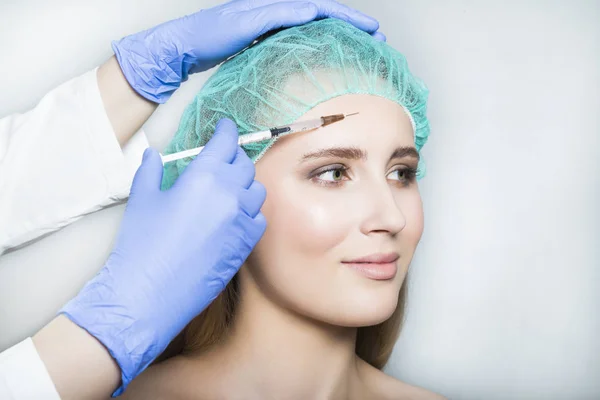 Doctor aesthetician makes face beauty injections to female patient