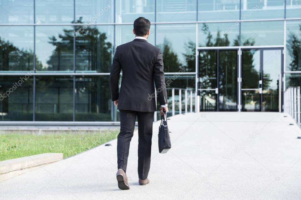 Businessman or worker standing in suit near office building