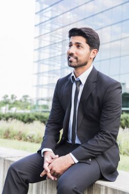 Başarılı bir iş adamı veya cam building yakınındaki elbiseli oturan işçi