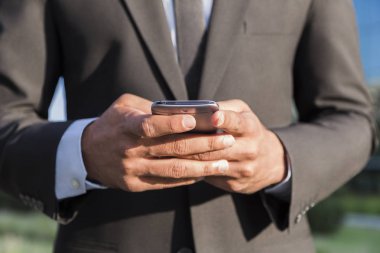 Elinde cep telefonu ile takım elbiseli işadamı veya işçi ayakta