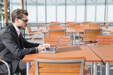 Erkek iş adamı veya alt masa ve bilgisayar üzerinde çalışan siyah elbiseli.