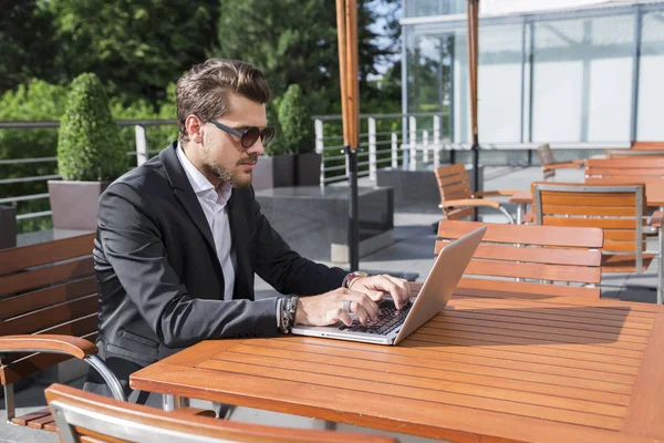 Erkek iş adamı veya alt masa ve bilgisayar üzerinde çalışan siyah elbiseli.