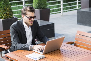 Erkek iş adamı veya alt masa ve bilgisayar üzerinde çalışan siyah elbiseli.