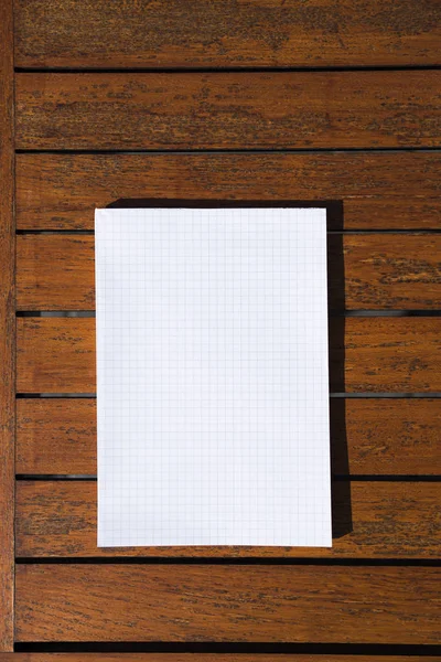 Bloc-notes simple blanc rectangulaire vide sur une table en bois orange dans un café ou un restaurant . — Photo