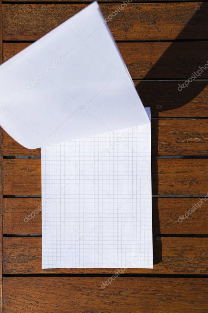Empty rectangular white simple notepad on orange wooden table in cafe or restaurant.
