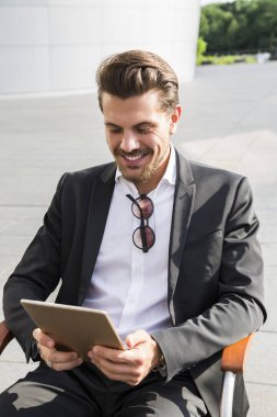 Erkek iş adamı veya alt sandalyede oturan tablet ile siyah elbiseli