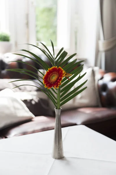 Flor gerbera roja naranja amarilla con hoja de palma verde en jarrón de metal en la mesa — Foto de Stock