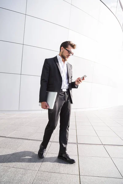 Homem de negócios ou trabalhador em terno preto com telefone inteligente — Fotografia de Stock