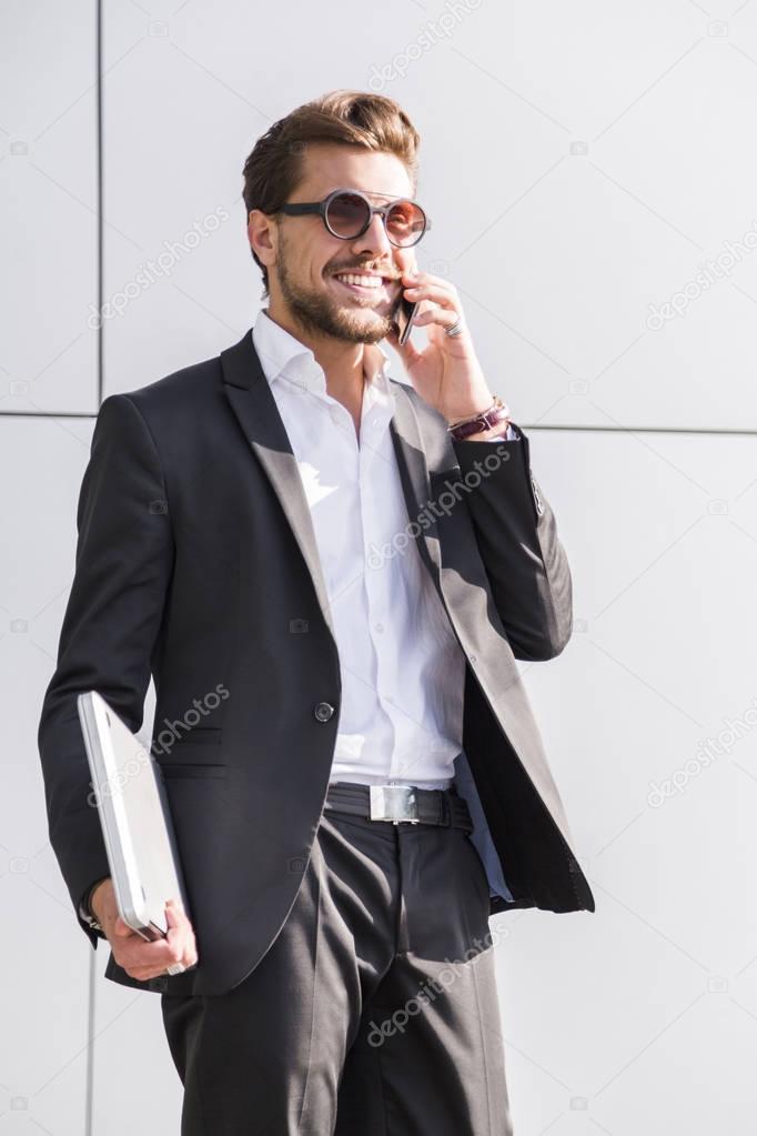 Male businessman or worker in black suit talking on phone