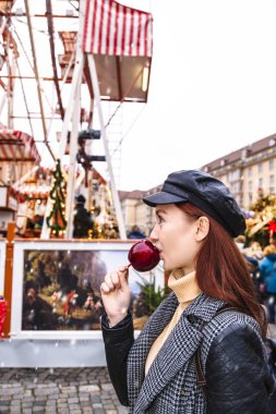 Genç kız Noel pazarında karamelli elma yiyor.