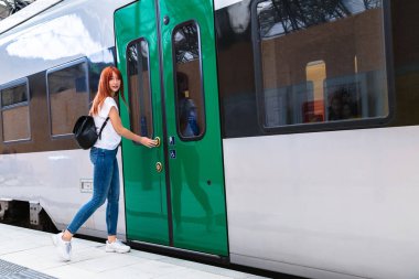 Sırt çantalı genç kız tren vagonuna girmeye çalışıyor.