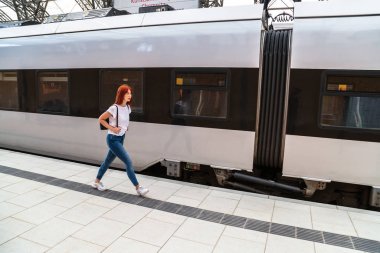 Kız istasyonda eğitime gider ve etrafa bakar.