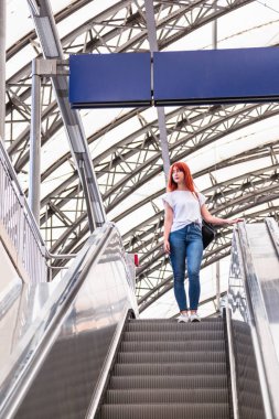 Kız merdivenlerden aşağı iniyor, elinde parmaklıklar tutarak.