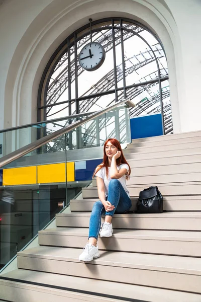 Menina com olhar pensativo senta-se nas escadas da estação — Fotografia de Stock