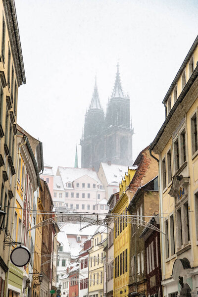 Snowy street in historic city of Meissen in winter with blurred image of castle on background