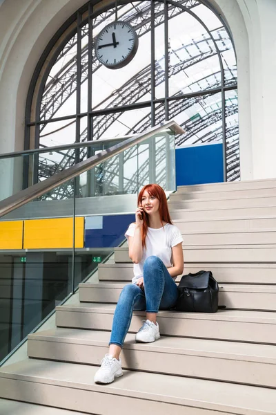 Девушка сидит на станции на лестнице разговаривает по телефону — стоковое фото