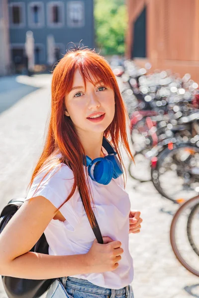 Menina ruiva bonito se divertindo na rua perto de bicicletas — Fotografia de Stock