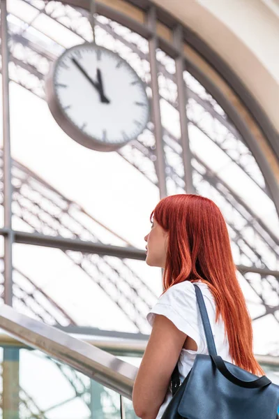 Menina na estação fica perto de arco com relógio de parede — Fotografia de Stock