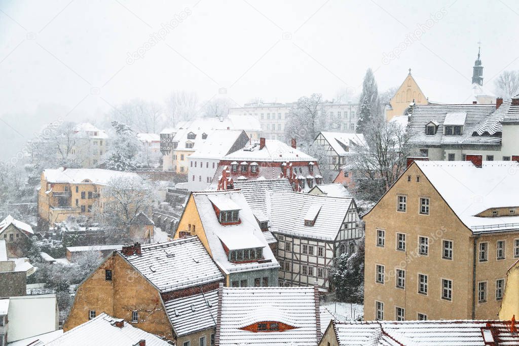 Roofs of old houses with snow in blizzard and fog