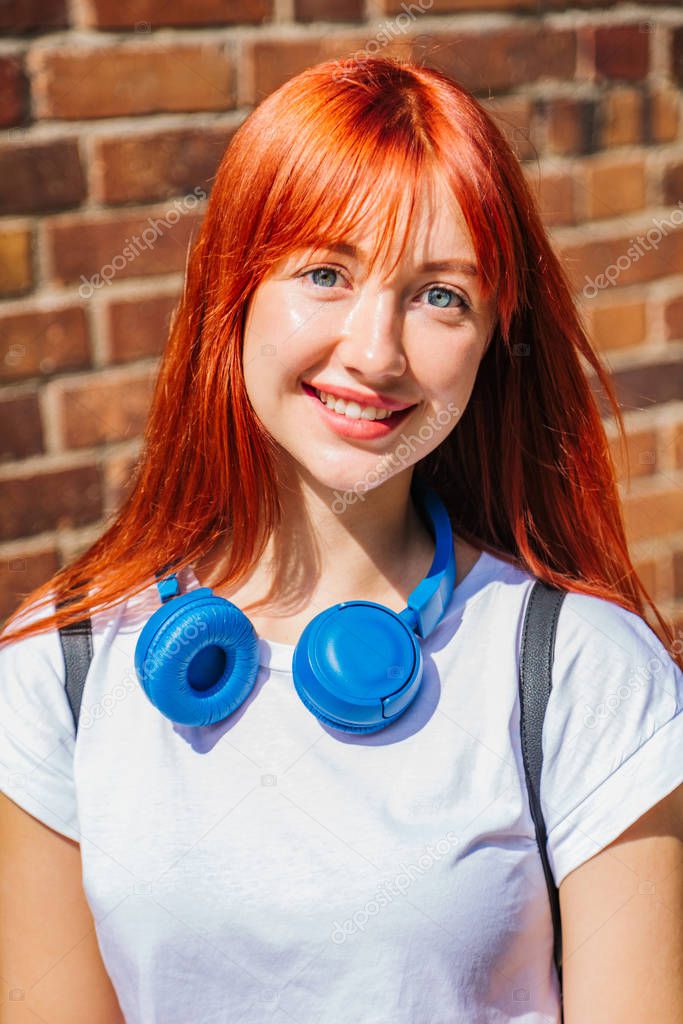 Portrait of red-haired girl in city in sunlight