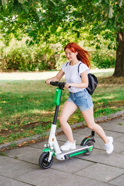 Giovane ragazza cavalca su scooter elettrico in giorno d'estate — Foto Stock