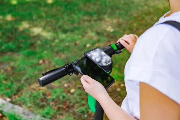Akıllı telefonlu bir kadın elektrikli scooter 'ın üzerinde duruyor.