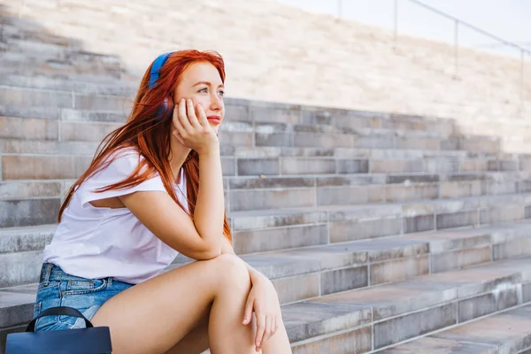 Jovem menina bonita senta-se nas escadas em desgaste da cidade — Fotografia de Stock