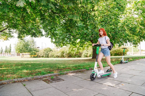Girl pushes off ground to start riding scooter — Stock Photo, Image