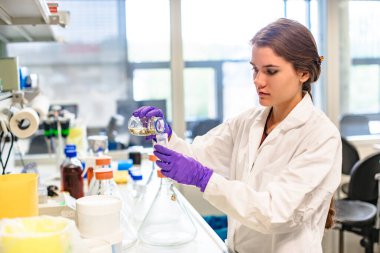 Laboratuvar asistanı test tüpüne sıvı dolduruyor.