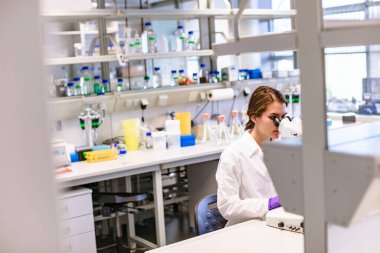 Laboratuvarda mikroskoba bakan bilim kadını.