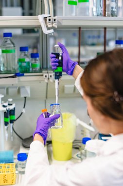 Kız test tüpünü tutuyor ve içine sıvı döküyor.