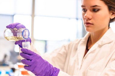 Laboratuvar asistanı test tüpüne sıvı dolduruyor.