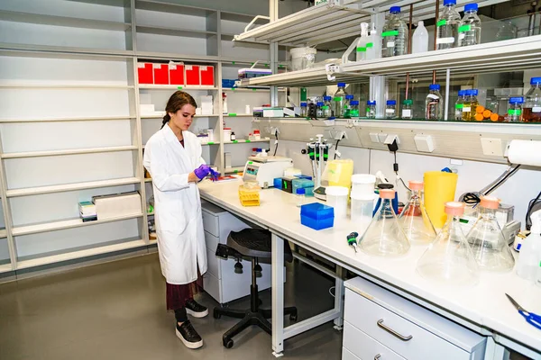 Вчений у білому лабораторному пальто, що стоїть за обладнанням — стокове фото